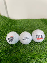 Load image into Gallery viewer, Three golf balls with Howard University logos on a grass surface
